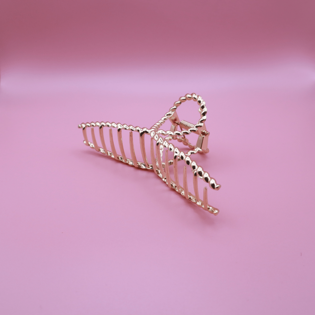 Golden Belle signature gold metal claw hair clip on pink background