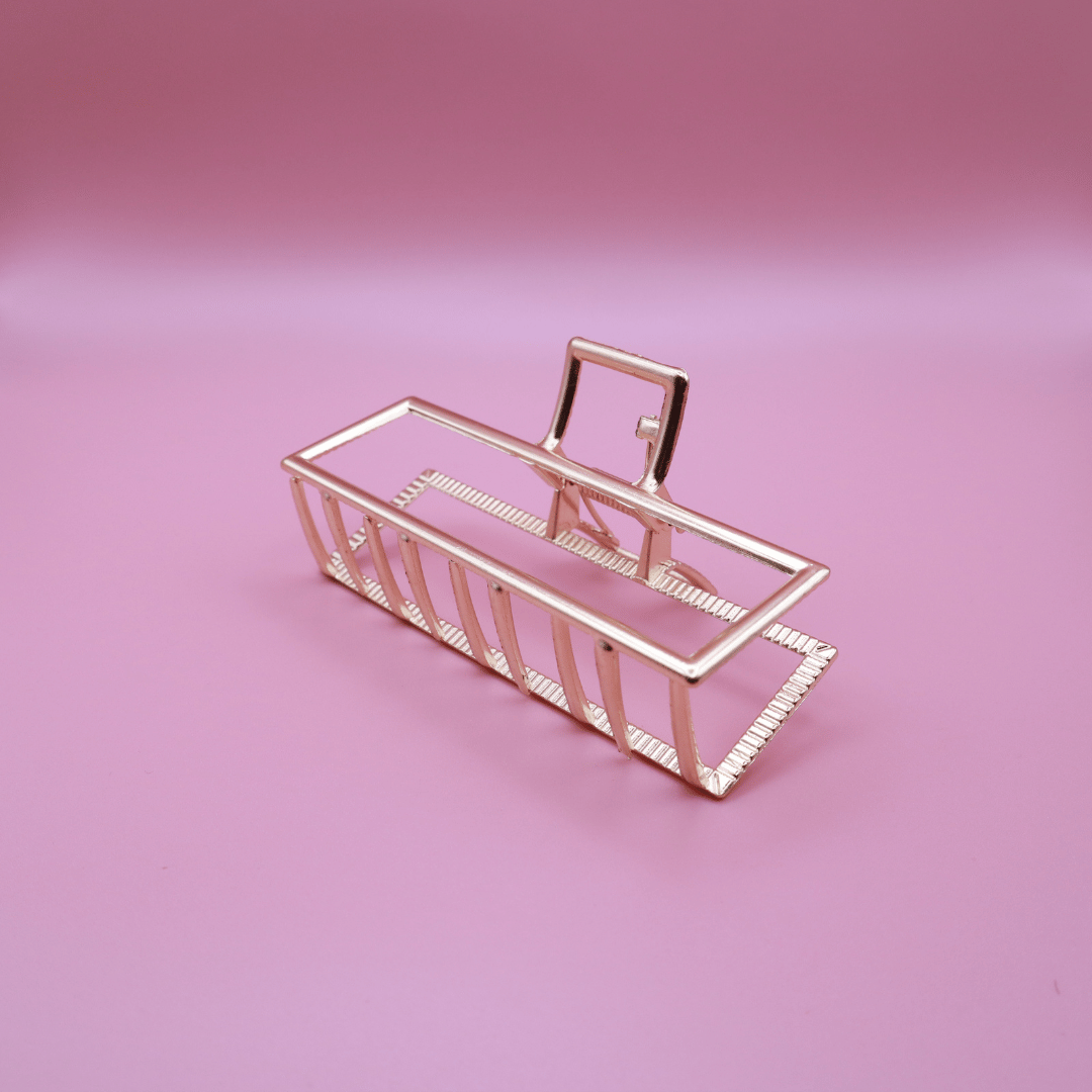 Golden Belle signature gold metal claw hair clip with rectangular design on pink background