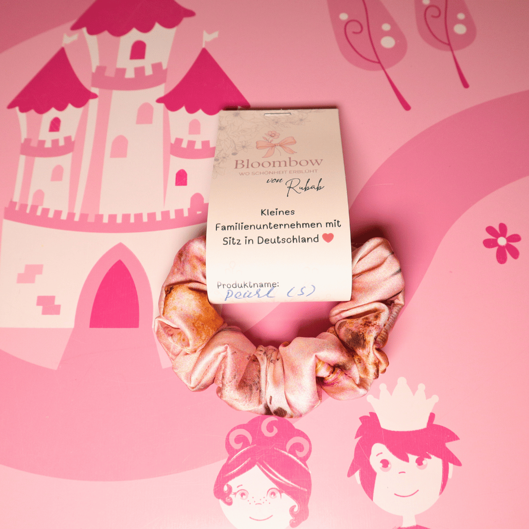 Scrunchie „Pearl“ in Rosa Floral vor pinkem Hintergrund mit Schlossmotiv.
