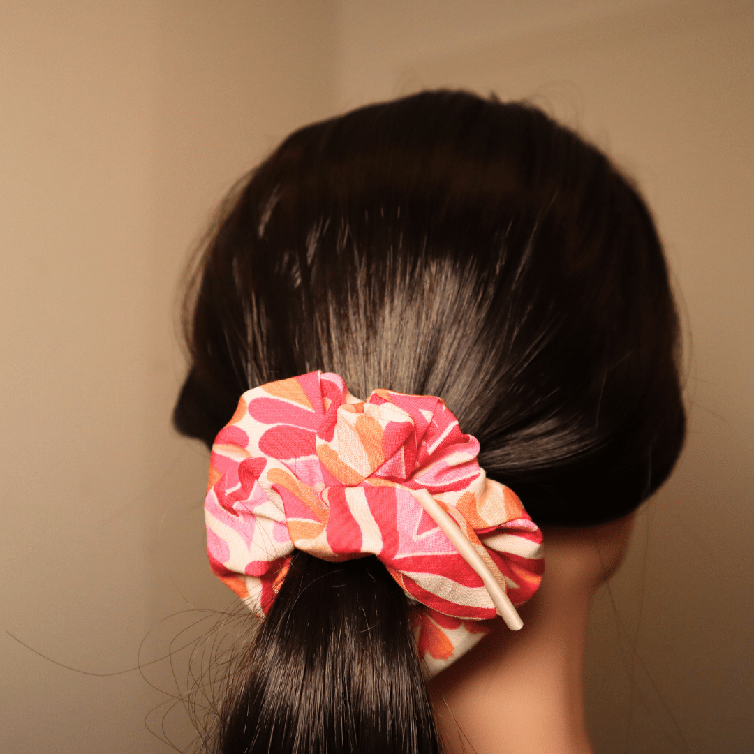Scrunchie Melody mit rosa, orange, rot abstraktem Muster im Haar.