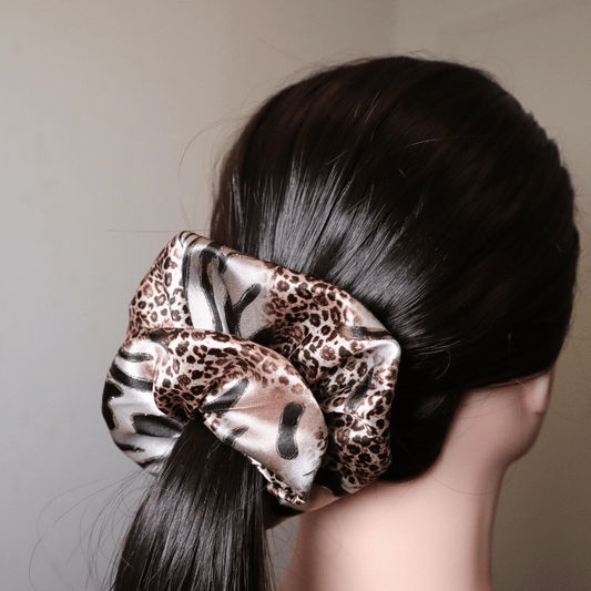 Scrunchie Tiggy in leopard print satin, providing gentle hair hold without breakage.