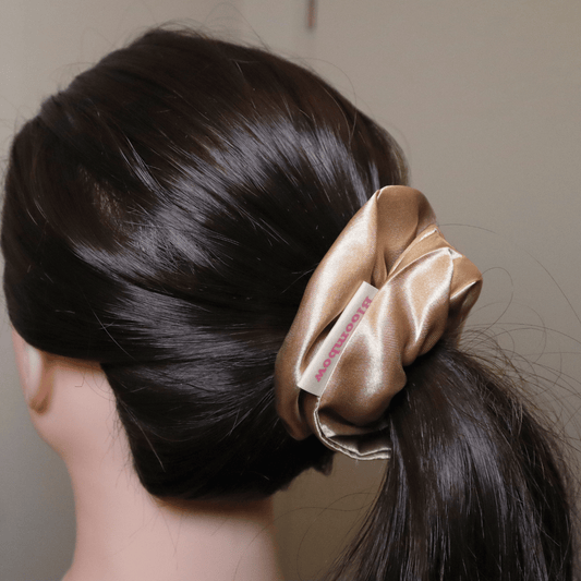Golden satin scrunchie holding ponytail, Daisy design.