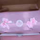PastelPetal Haarklammer Set in pastel colors with pink bow stickers on pink tissue paper inside a box, eco-friendly packaging.