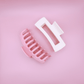 Pastel-colored Haarklammern set with pink and white clips on pink background, stylish and gentle on hair.