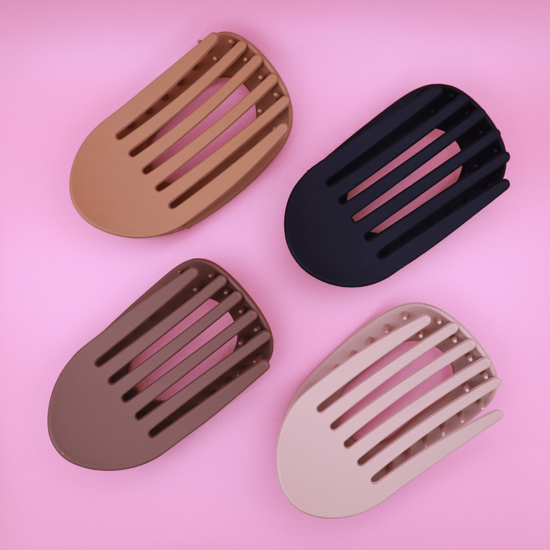 Haarklammer-Set Classic Calm with four matte neutral-tone claw clips in beige, light brown, dark brown, and matte black on pink background.