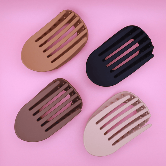 Haarklammer-Set Classic Calm with four matte neutral-tone claw clips in beige, light brown, dark brown, and matte black on pink background.