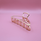 Golden metal claw hair clip from Golden Belle signature set on pink background