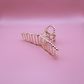 Golden Belle signature gold metal claw hair clip on pink background